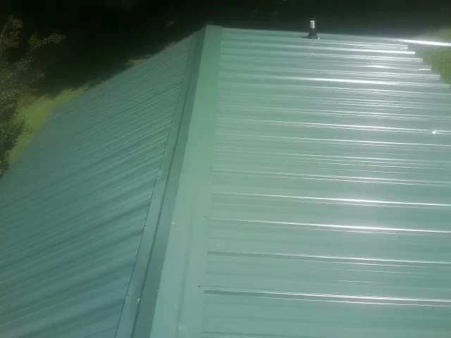 New green metal panels meeting at the ridge of a roof — Flat Roof Repair work by our crew in Potlatch