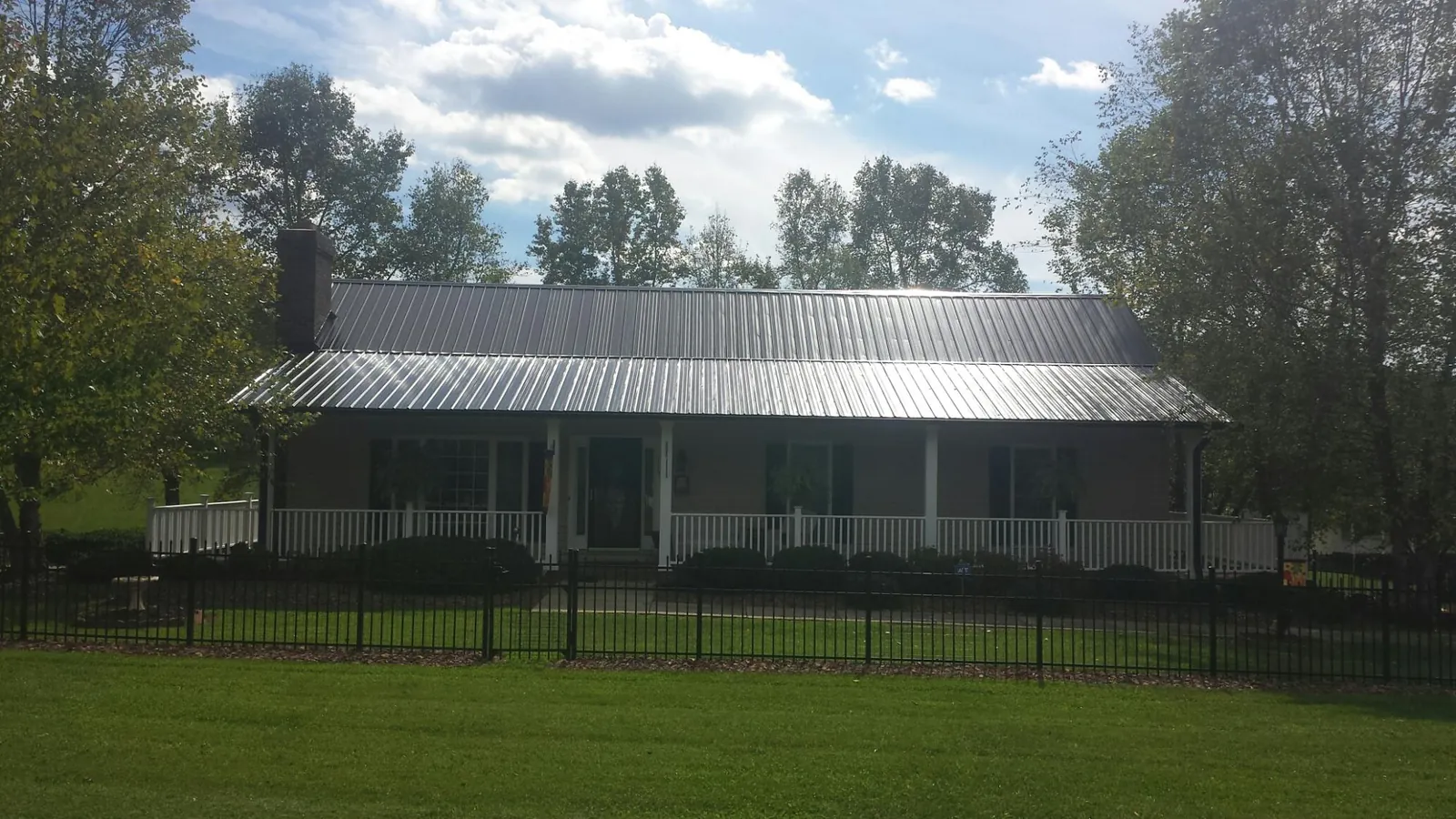 Gray metal roof on a brick ranch with a full width front porch — Gutter Guard Installation work by our crew in Potlatch