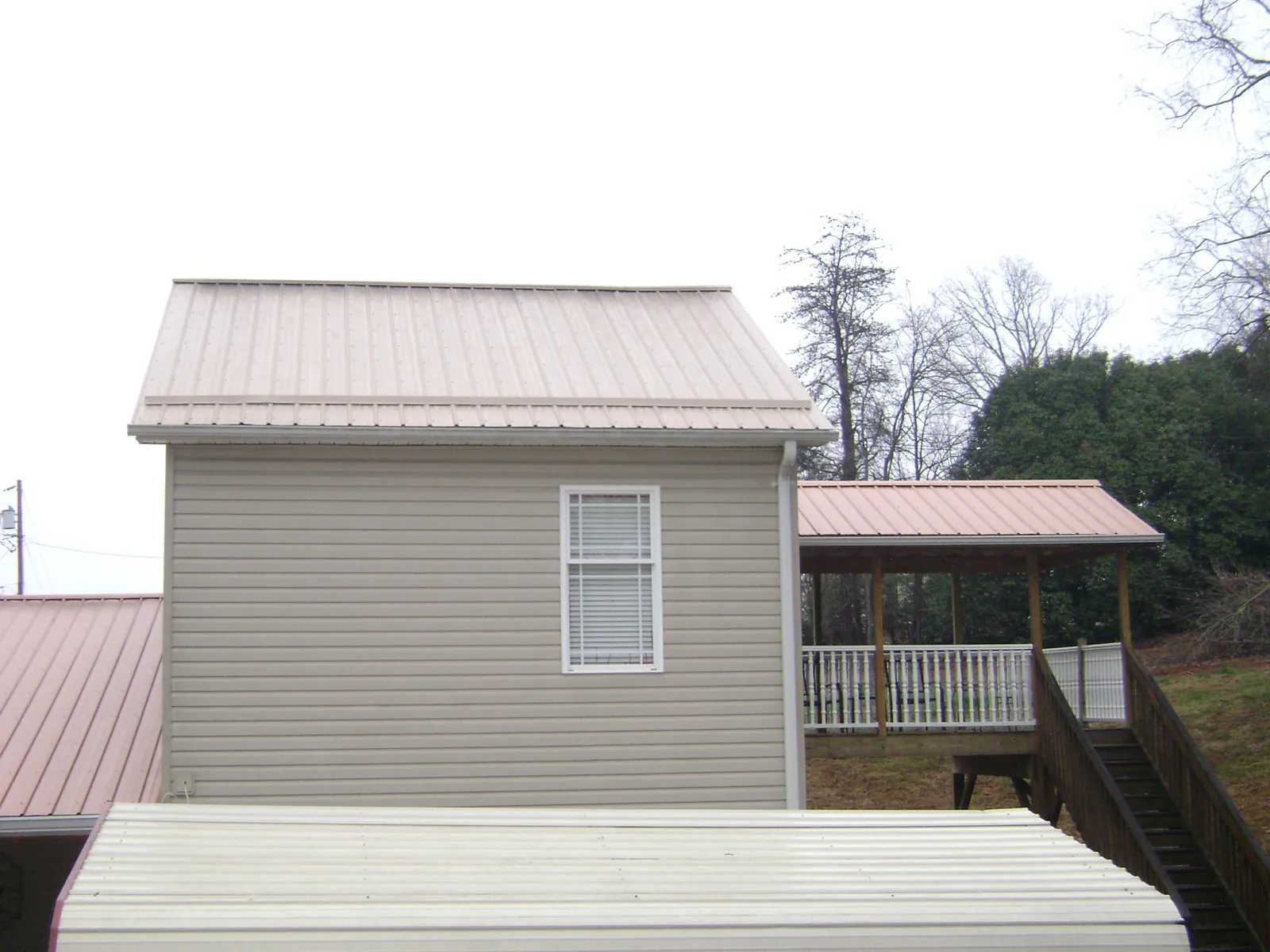 Tan metal roofs on a two story addition and attached porch, from a Roof Replacement job in Potlatch