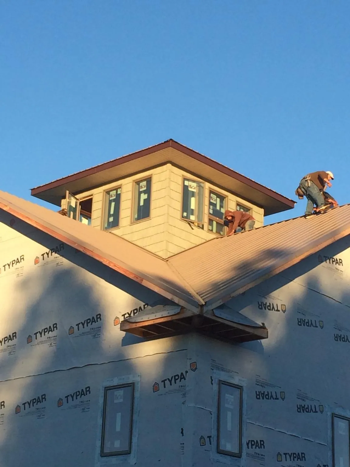 Roofers working around a rooftop cupola on a new metal roof at sunset — Roof Waterproofing in Potlatch by Roofing Brothers